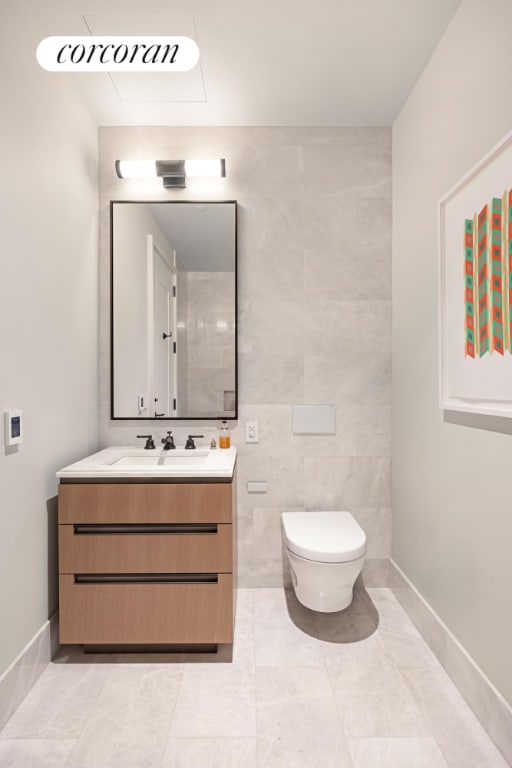 bathroom with toilet, baseboards, tile walls, and vanity