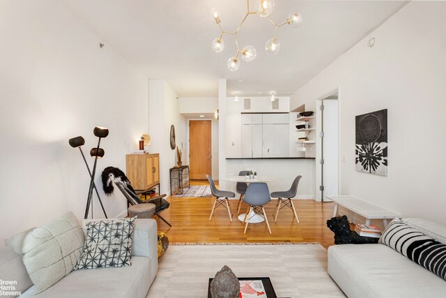 dining room with light wood-type flooring, an AC wall unit, and a notable chandelier