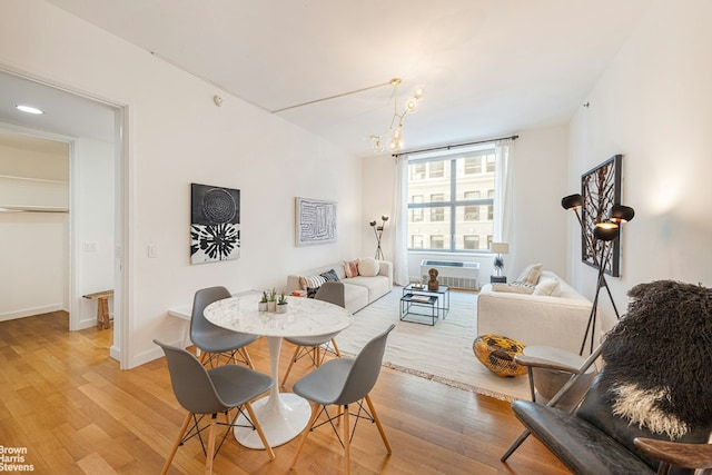 dining room with light wood-type flooring, an AC wall unit, and a notable chandelier