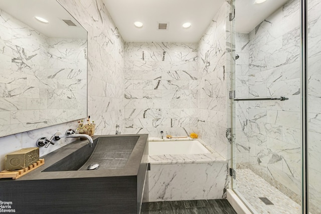 bathroom featuring independent shower and bath, tile walls, and vanity