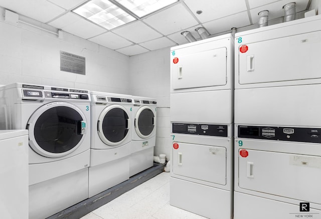 community laundry room featuring concrete block wall, separate washer and dryer, and stacked washing maching and dryer