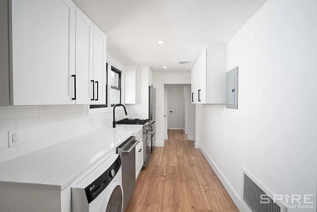 kitchen with visible vents, decorative backsplash, washer / dryer, appliances with stainless steel finishes, and white cabinetry