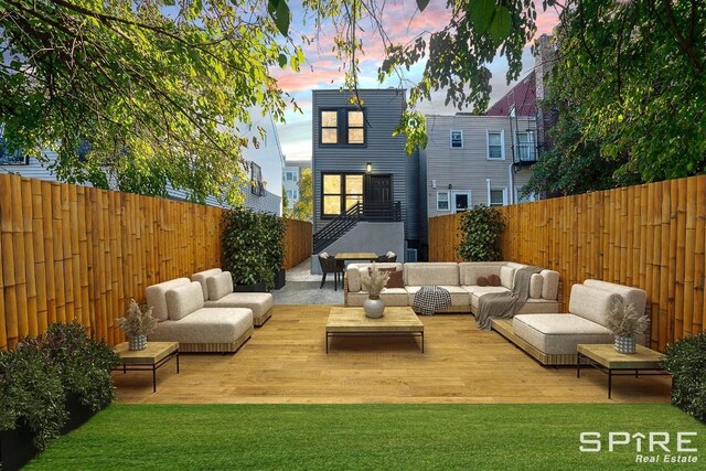 back of house at dusk featuring a yard, a fenced backyard, and outdoor lounge area