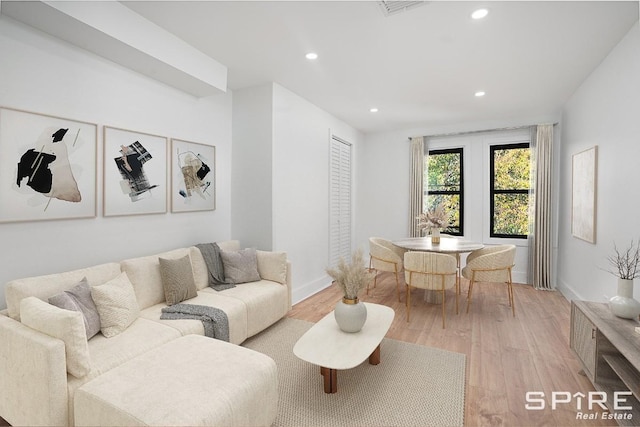 living room with recessed lighting, baseboards, and light wood-style floors