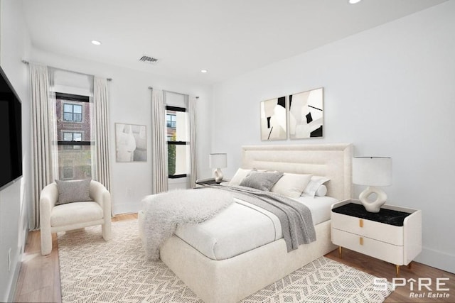 bedroom with baseboards, wood finished floors, visible vents, and recessed lighting