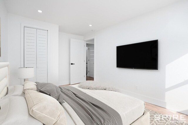 bedroom featuring a closet, recessed lighting, light wood-style flooring, and baseboards