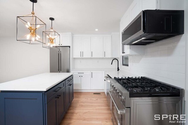 kitchen with pendant lighting, high quality appliances, light wood-type flooring, light countertops, and white cabinets