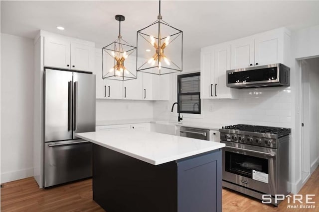 kitchen featuring white cabinets, a kitchen island, appliances with stainless steel finishes, and light countertops