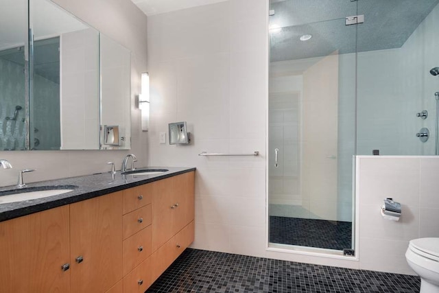 bathroom with toilet, a shower with shower door, tile walls, tile patterned flooring, and vanity