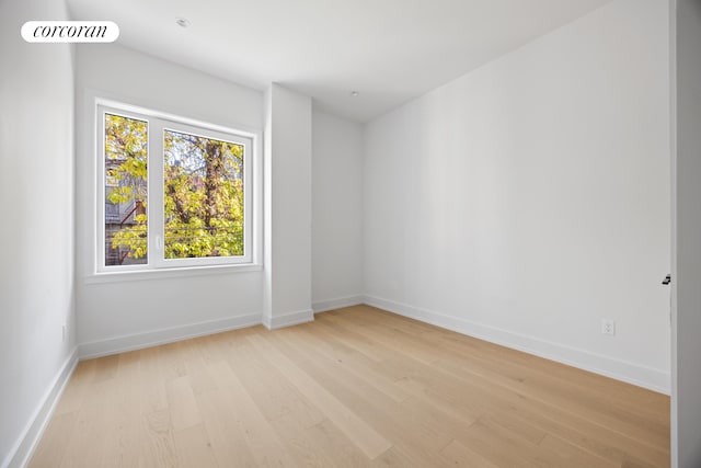 empty room with light wood-type flooring, visible vents, and baseboards