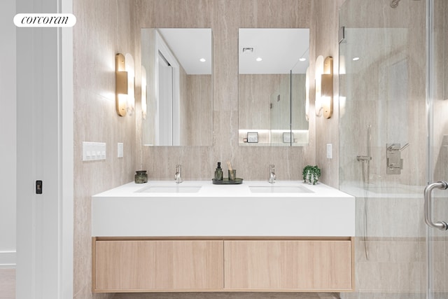 bathroom with a stall shower, a sink, and tile walls