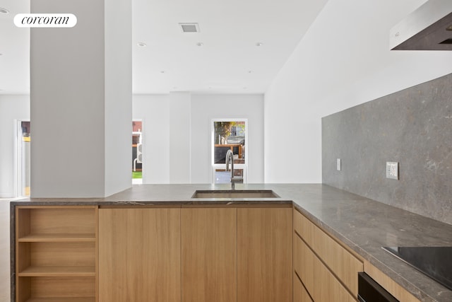 kitchen with a peninsula, modern cabinets, a sink, and visible vents