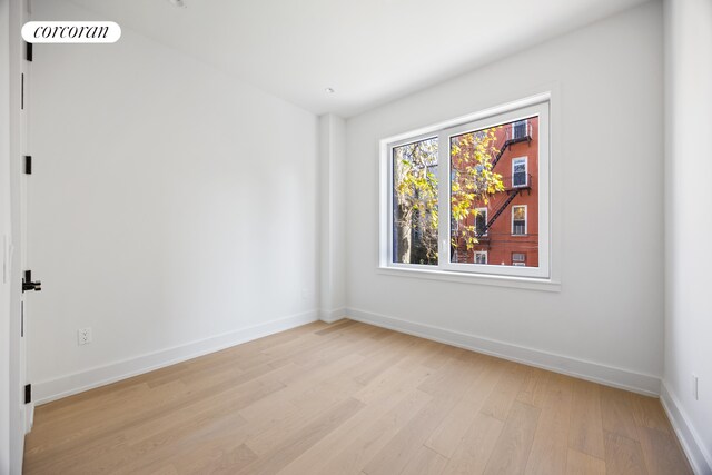 unfurnished room with light wood finished floors, visible vents, and baseboards