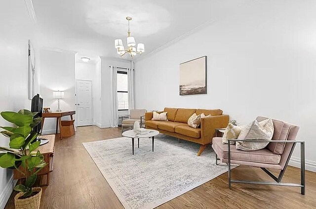 living room featuring crown molding, a chandelier, and light wood-type flooring