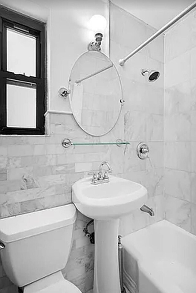 bathroom featuring tiled shower / bath, tile walls, and toilet