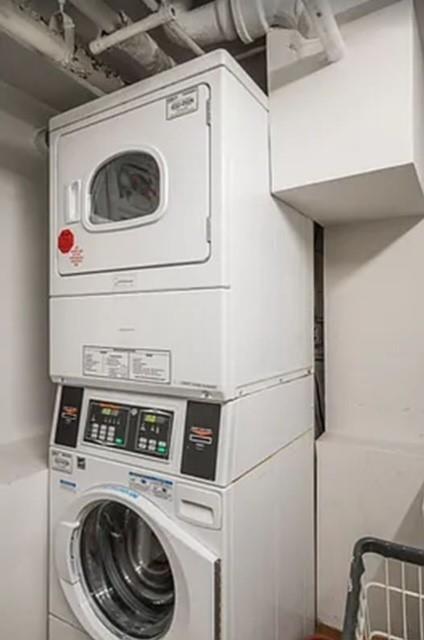 clothes washing area featuring stacked washing maching and dryer