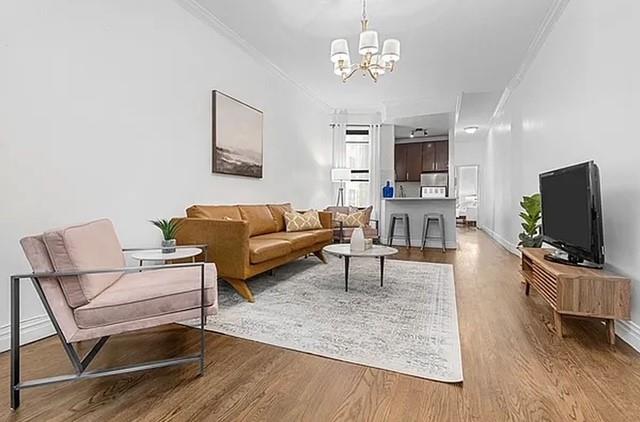 20 E 88th St Unit 2B, New York City, NY 10128 - living room with ornamental molding, a chandelier, and wood finished floors