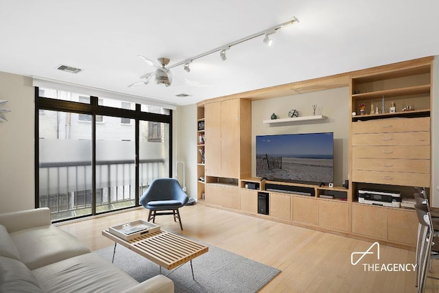 living room featuring floor to ceiling windows, visible vents, and light wood finished floors