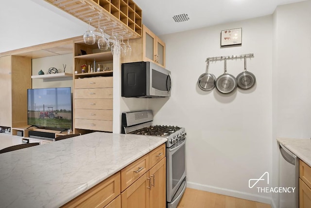 kitchen with stainless steel appliances, visible vents, baseboards, light stone countertops, and open shelves