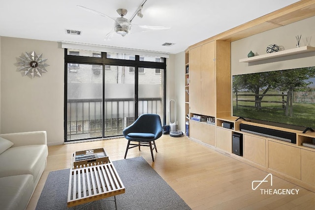 interior space featuring visible vents, a ceiling fan, light wood finished floors, a wall of windows, and rail lighting