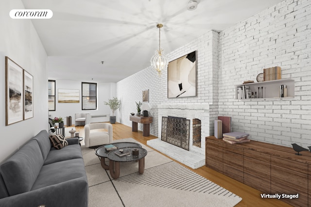 living room featuring visible vents, brick wall, radiator heating unit, wood finished floors, and a fireplace