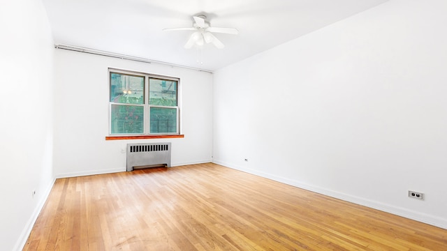 unfurnished room with radiator, baseboards, light wood-type flooring, and ceiling fan