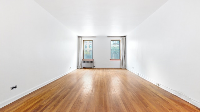 unfurnished room featuring light wood-style flooring, radiator, and baseboards