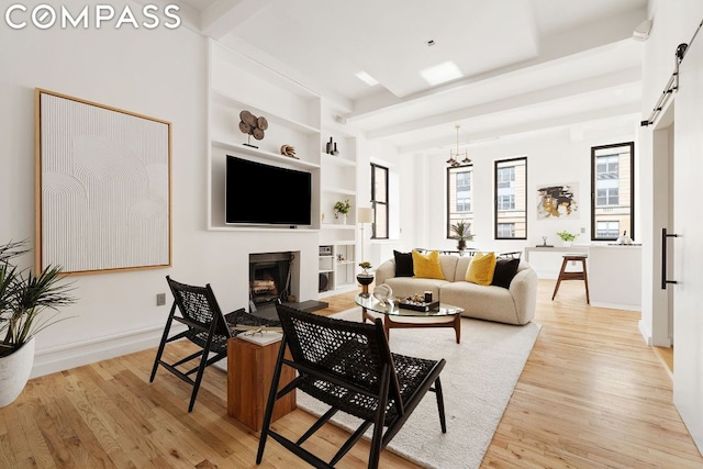 living room featuring a notable chandelier, light hardwood / wood-style flooring, and built in shelves