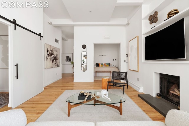 living room with a barn door, a tiled fireplace, and hardwood / wood-style floors