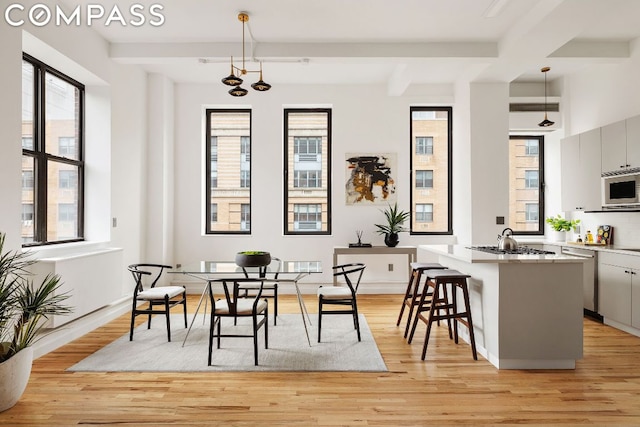 dining space featuring beamed ceiling and light hardwood / wood-style floors