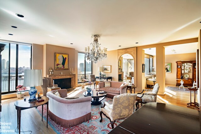 living room with baseboard heating, floor to ceiling windows, a chandelier, and light wood-type flooring