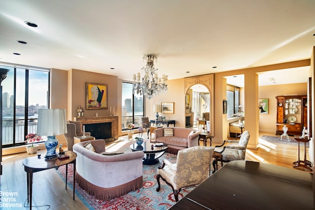 living room featuring a baseboard heating unit, expansive windows, wood finished floors, a fireplace, and a chandelier