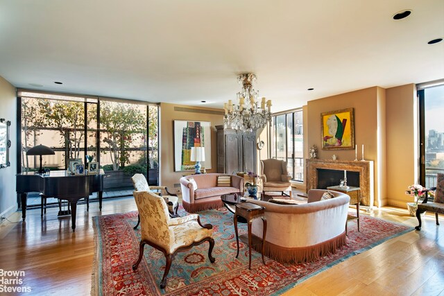 living room featuring wood-type flooring, plenty of natural light, a high end fireplace, and a wall of windows