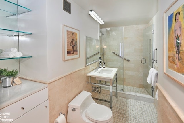 bathroom featuring toilet, tile walls, a shower with shower door, and sink