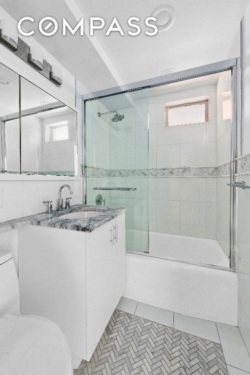 full bathroom featuring vanity, tile patterned floors, enclosed tub / shower combo, and toilet