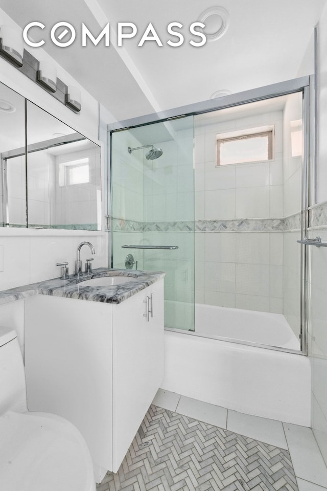 bathroom with tile patterned flooring, shower / bath combination with glass door, vanity, and toilet