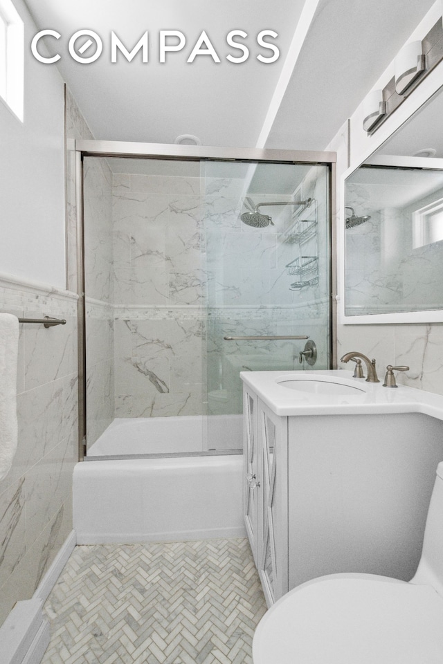 full bath with toilet, vanity, tile walls, and enclosed tub / shower combo