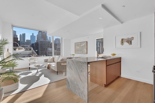 611 W 56th St Unit 7A, New York City, NY 10019 - kitchen with light wood-style flooring, a view of skyline, a peninsula, and stone countertops