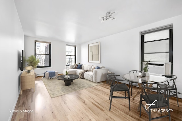 living room featuring a baseboard radiator, cooling unit, wood finished floors, baseboards, and baseboard heating