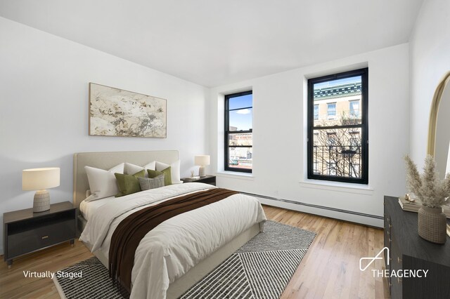 bedroom featuring a baseboard heating unit and light wood-type flooring