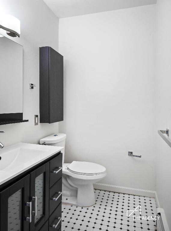 bathroom with toilet, a baseboard radiator, baseboards, and vanity