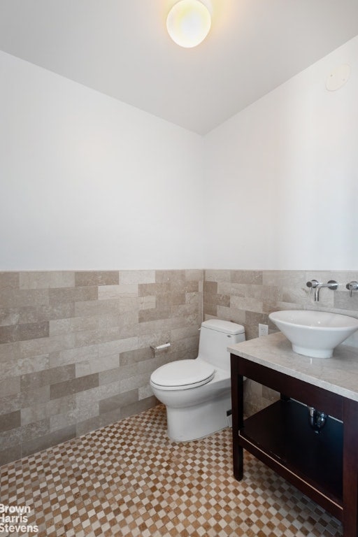 bathroom featuring sink, tile patterned floors, toilet, and tile walls