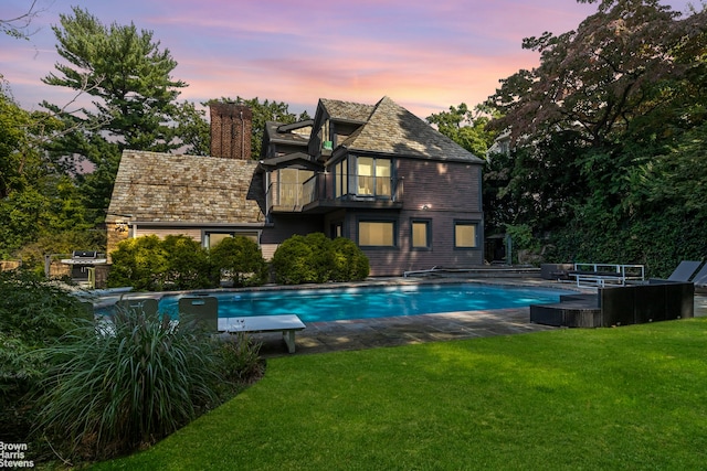 outdoor pool featuring a yard and grilling area