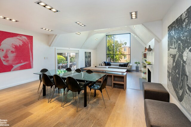 dining space featuring light wood-type flooring, a healthy amount of sunlight, lofted ceiling, and baseboards