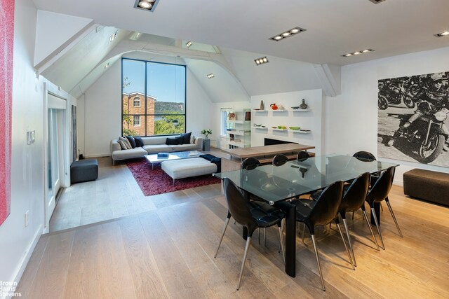 dining room with light wood-style floors and vaulted ceiling