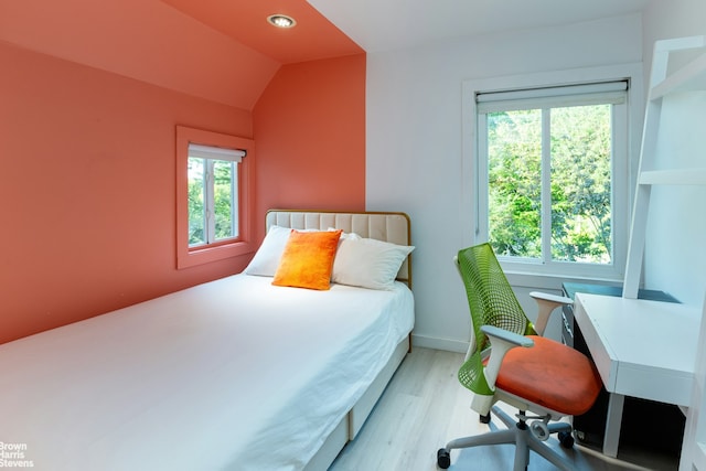 bedroom featuring light wood-type flooring, multiple windows, and vaulted ceiling