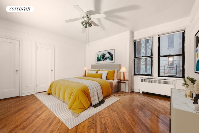 bedroom with ceiling fan, radiator heating unit, and dark hardwood / wood-style flooring