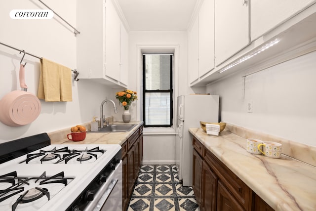 kitchen with white cabinetry, sink, white fridge, gas range, and dark brown cabinets