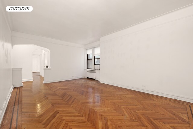 unfurnished room with ornamental molding, radiator heating unit, and light parquet floors