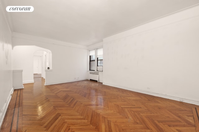 spare room featuring dark parquet flooring and radiator heating unit